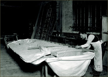 A worker attaching the fabric covering to a wing in the Wright factory.