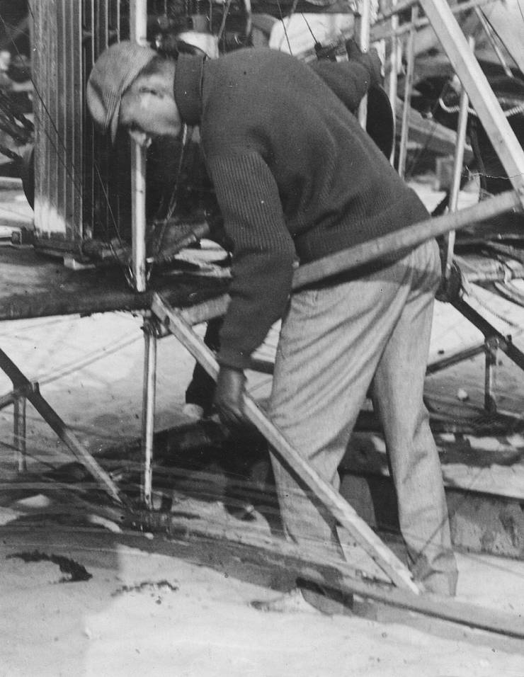 Walter Brookins setting up Wright transitional aircraft for flight, possibly adjusting the balance of the machine on the launching dolley.