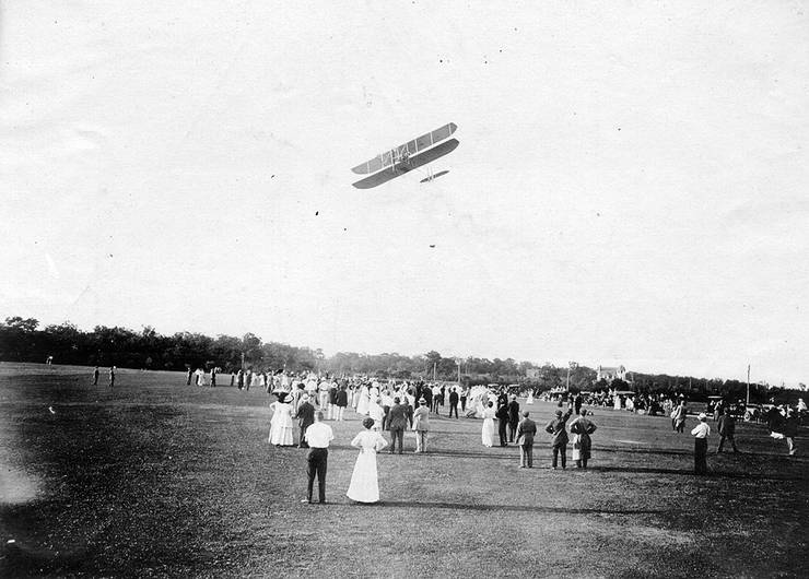 Early Wright Model B in flight over crowd.