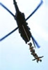 U.S. Army Special Forces personnel attached to Special Patrol Insertion-Extraction (SPIE) rigging are hoisted into the air by an MH-60G Pave Hawk helicopter. 